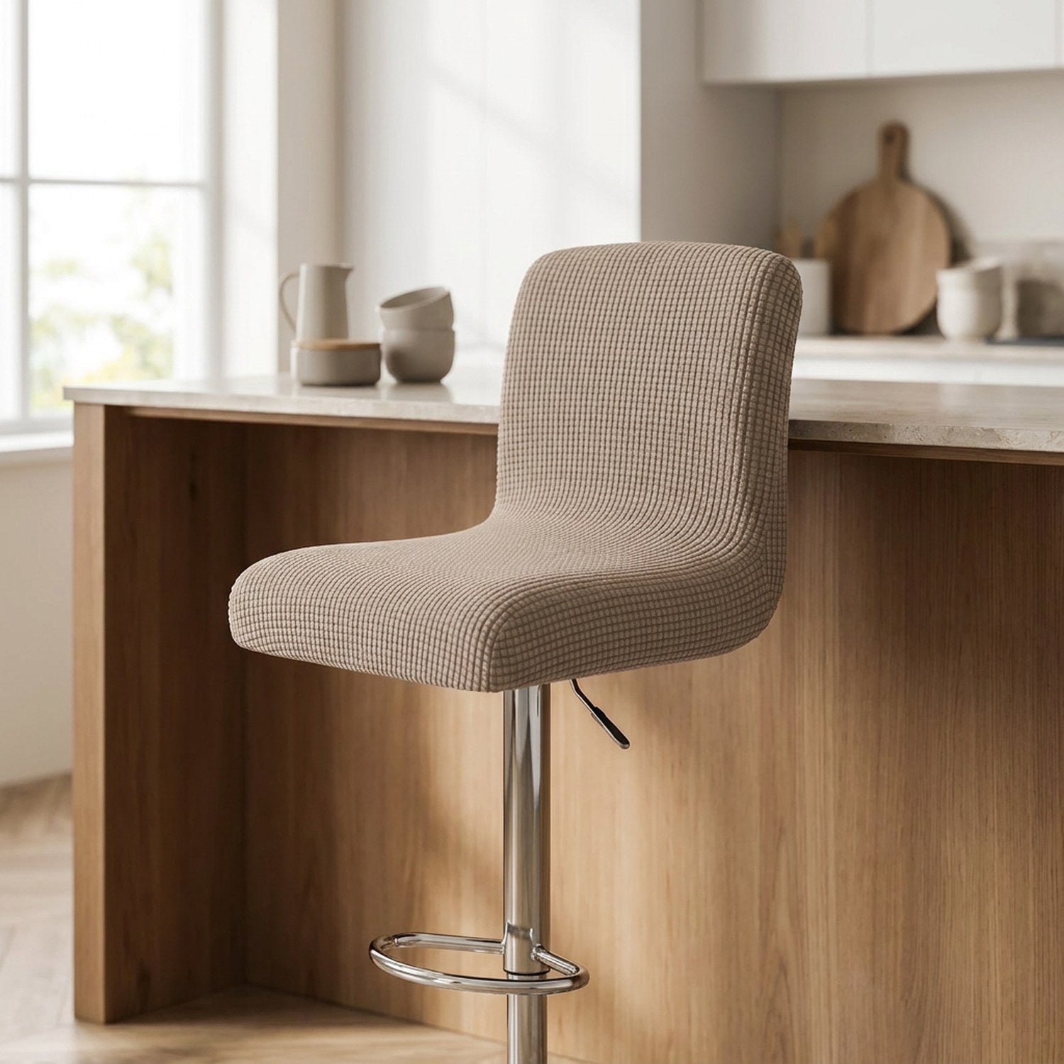 Housse de chaise de bar en jacquard texturé beige installée sur un tabouret dans une cuisine lumineuse