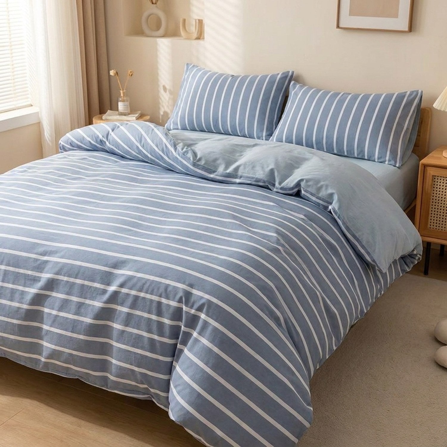 Housse de couette rayee bleue et blanche posee sur un lit fait dans une chambre lumineuse