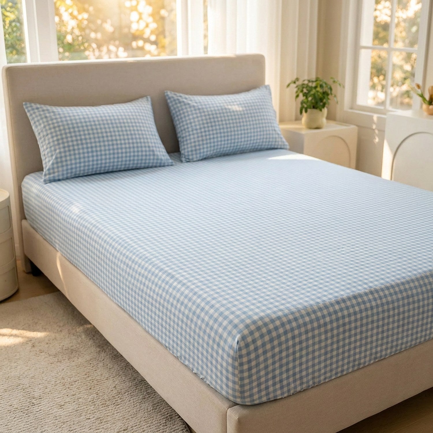 Drap housse à carreaux vichy bleu et blanc pose sur un lit fait dans une chambre lumineuse