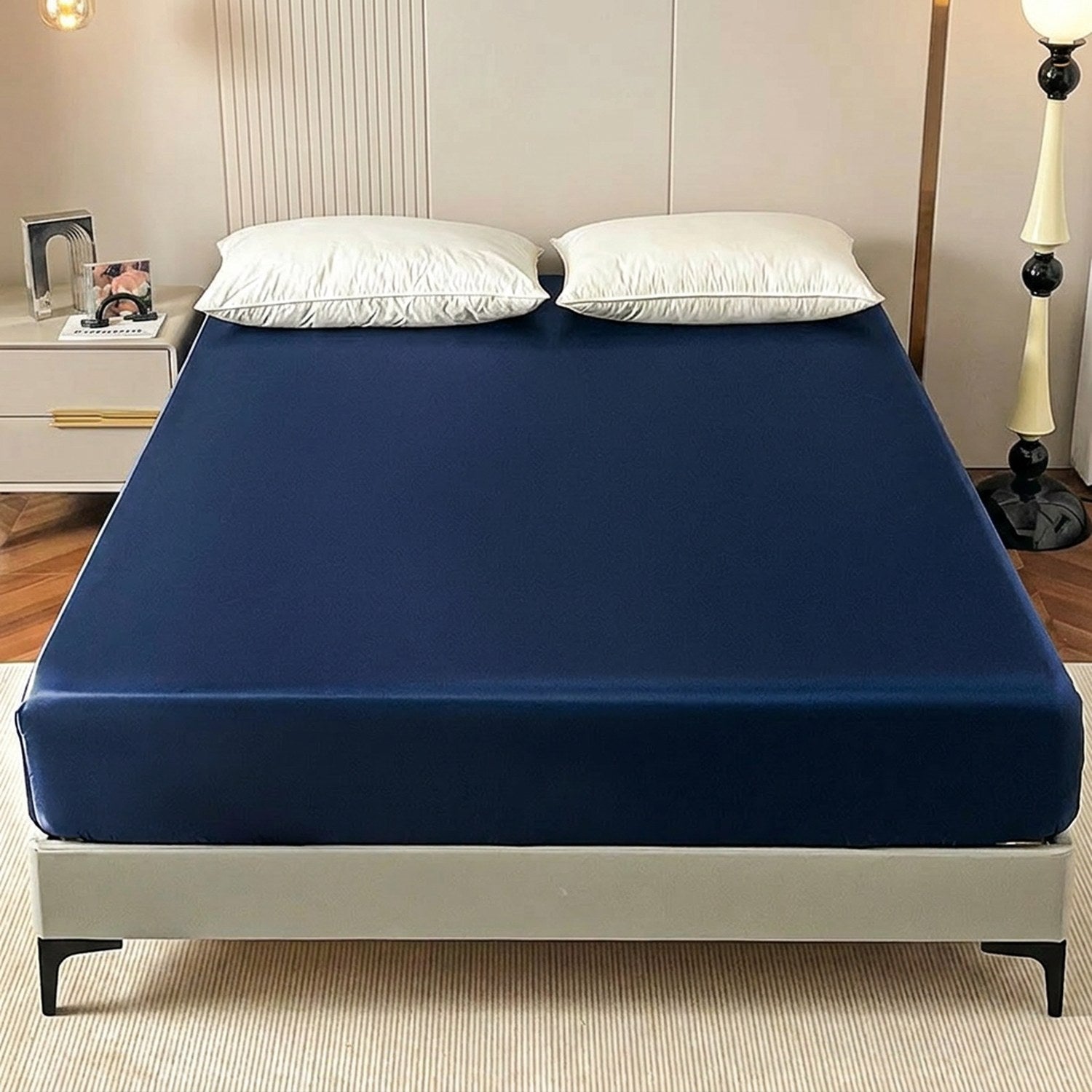 Drap-housse satin bleu marine élastique installé sur un lit dans une chambre chaleureuse