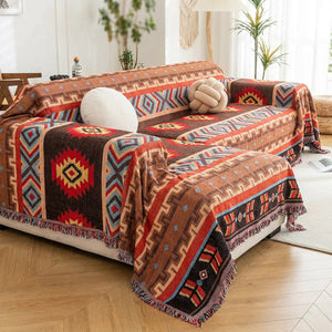 Couvre-lit amérindien aux motifs aztèques rouge et brun avec pompons drapé sur un canapé