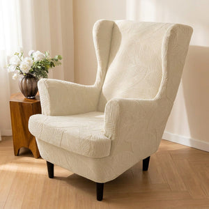 Fauteuil bergère habillé d'une housse crème à motif feuilles jacquard dans un salon lumineux