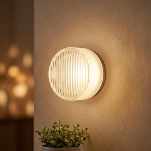 Applique murale LED ronde blanche au verre côtelé diffusant une lumière douce dans un salon moderne