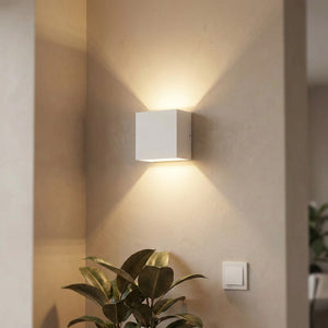 Applique murale LED blanche au design épuré diffusant une lumière chaleureuse dans un salon moderne