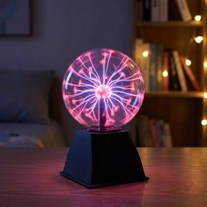 Lampe boule de plasma en verre avec éclairs violets et roses allumée sur une table de nuit