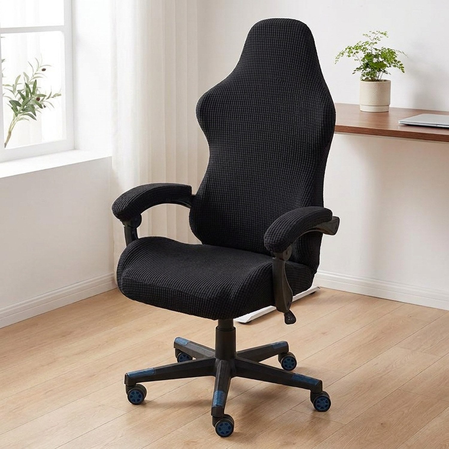Housse de chaise gaming noire en tissu maille sur une chaise de bureau à accoudoirs dans un intérieur moderne