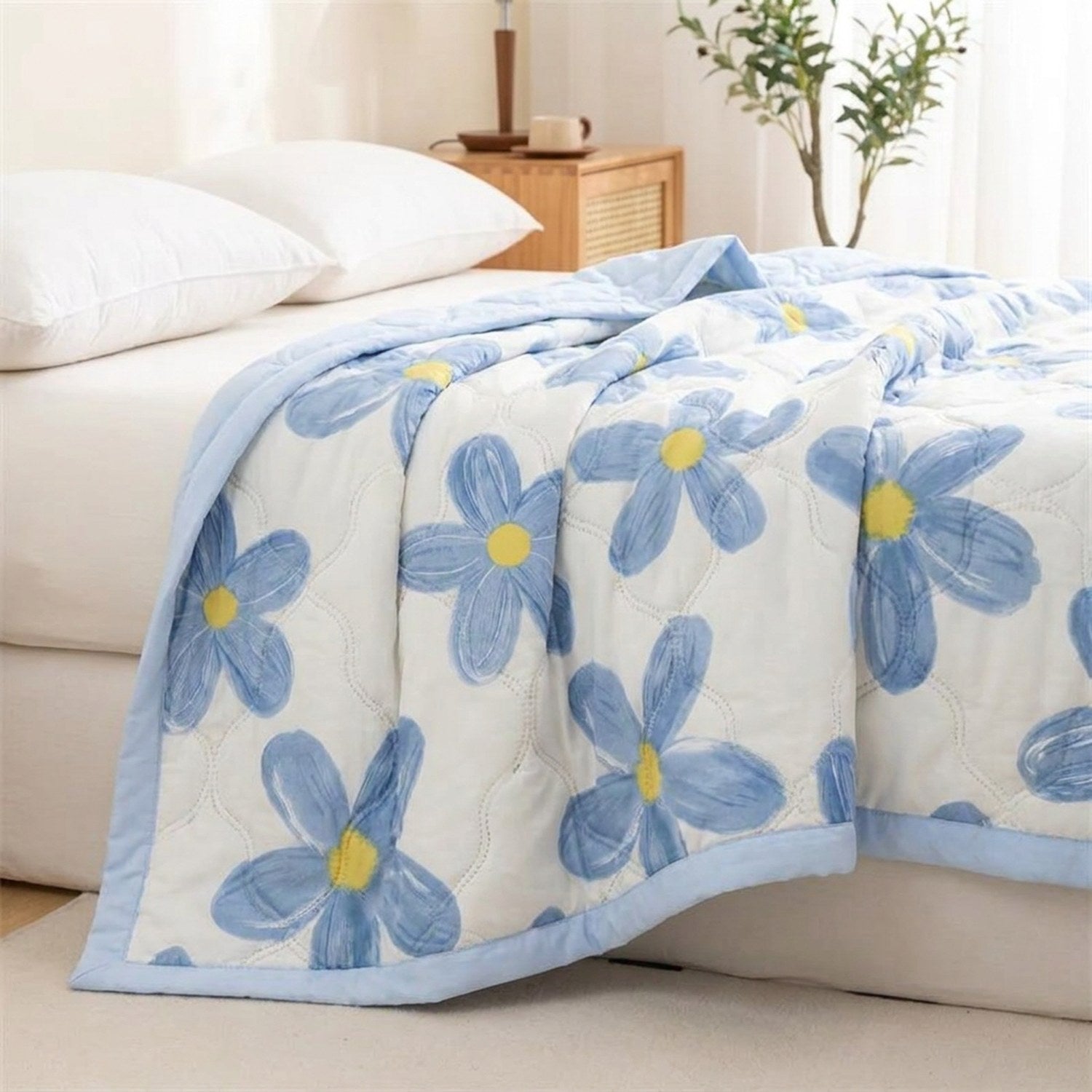 Couverture d'été légère à motif floral bleu gaufré posée sur un lit dans une chambre lumineuse