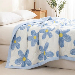 Couverture d'été légère à motif floral bleu gaufré posée sur un lit dans une chambre lumineuse