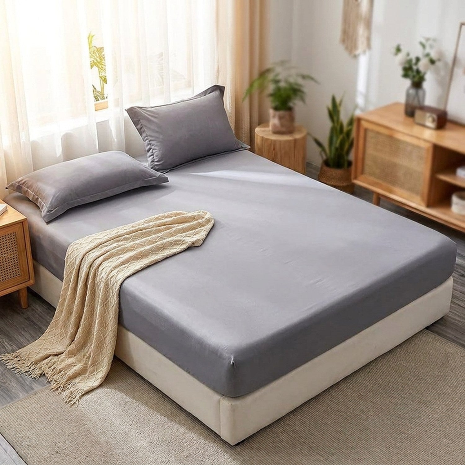 Drap-housse gris satin brossé installé sur un lit fait dans une chambre chaleureuse