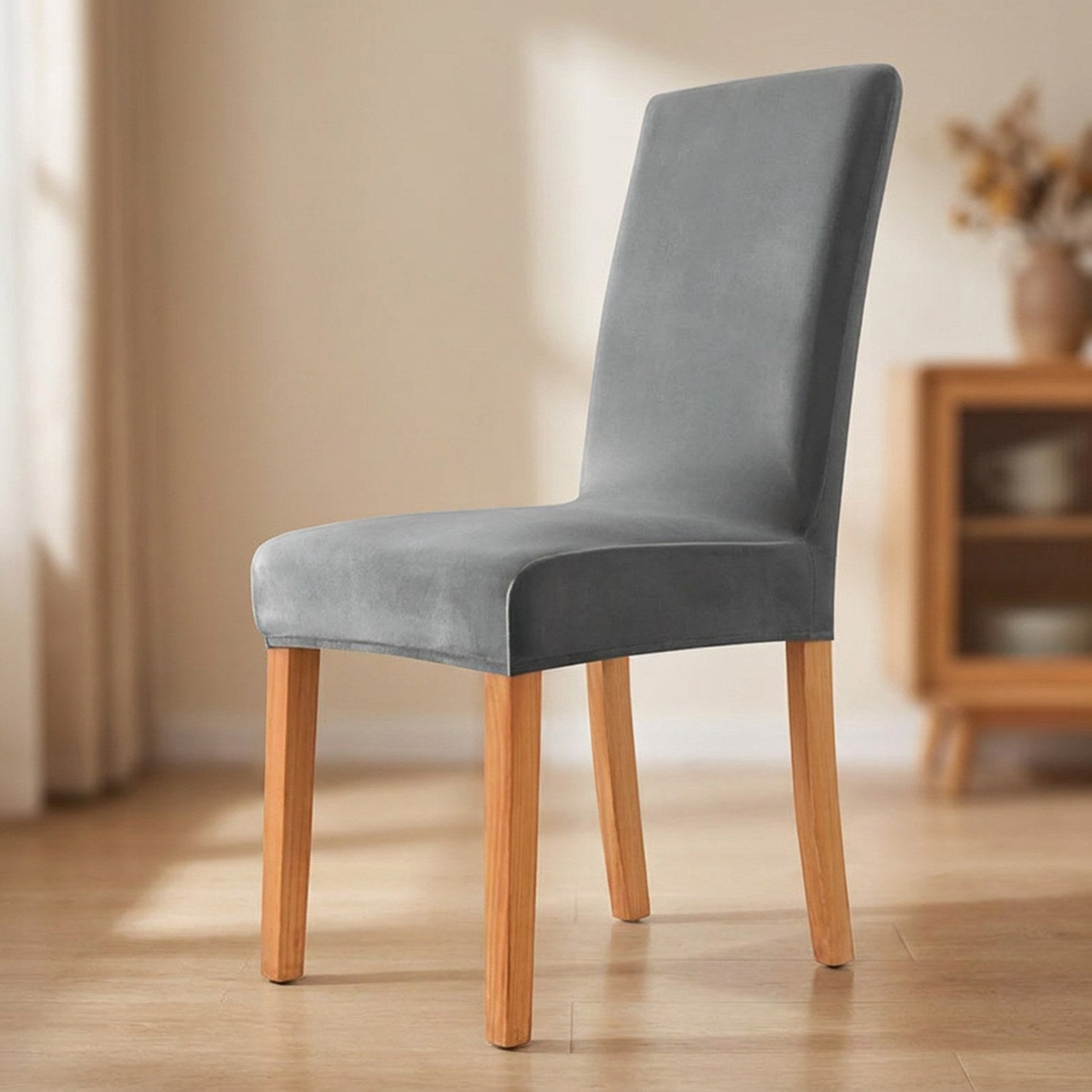 Housse de chaise grise en velours moelleux installée sur une chaise de salle à manger