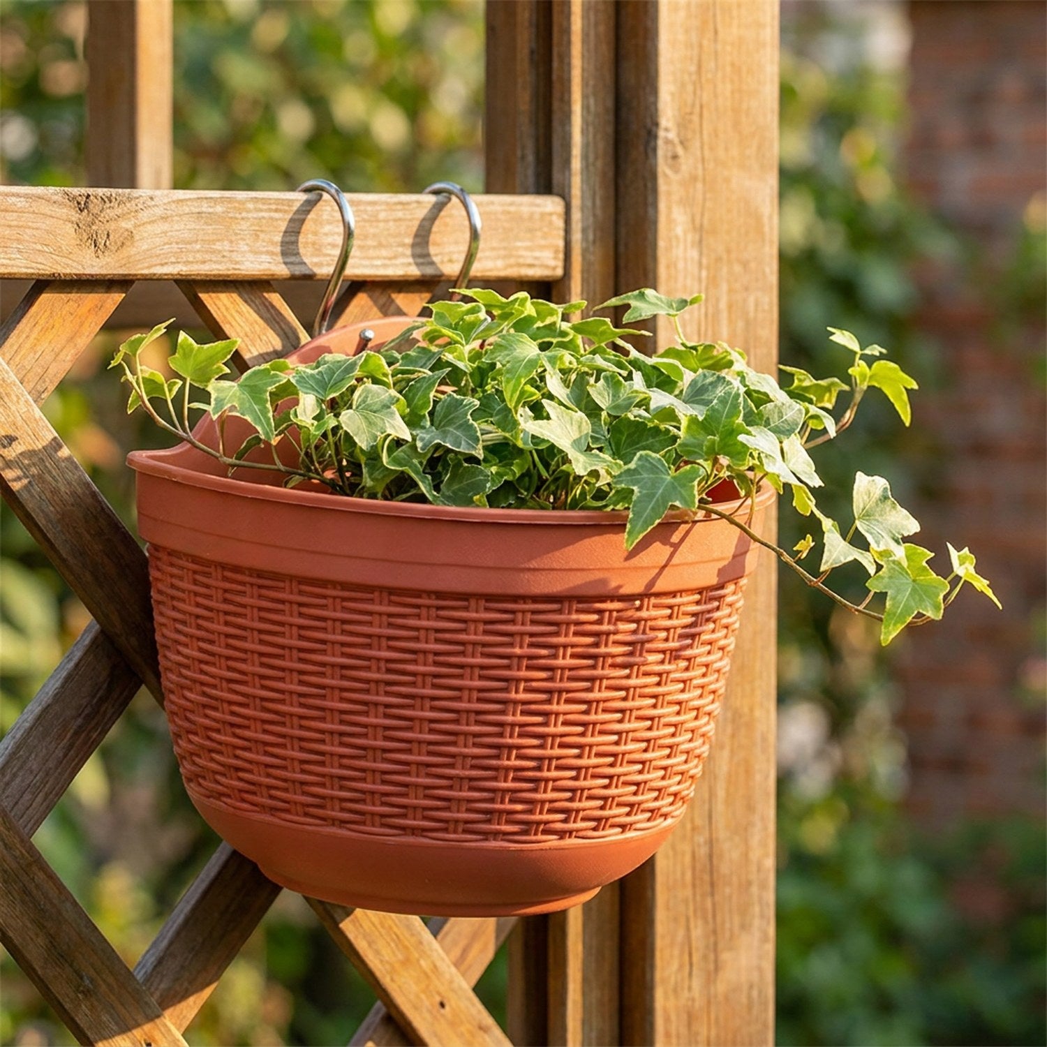 Pot de fleur mural en imitation rotin terracotta avec lierre vert sur treillis bois