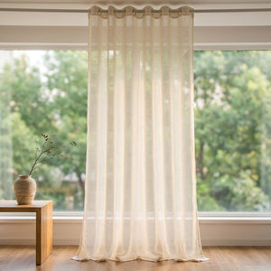 Voilage tulle beige transparent suspendu à une tringle devant une grande fenêtre lumineuse