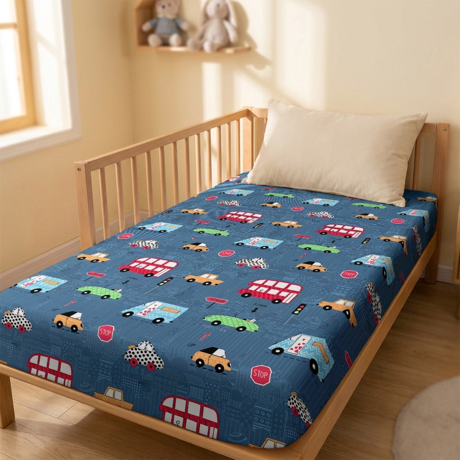 Drap housse bébé bleu imprimé de voitures et bus colorés sur un lit à barreaux