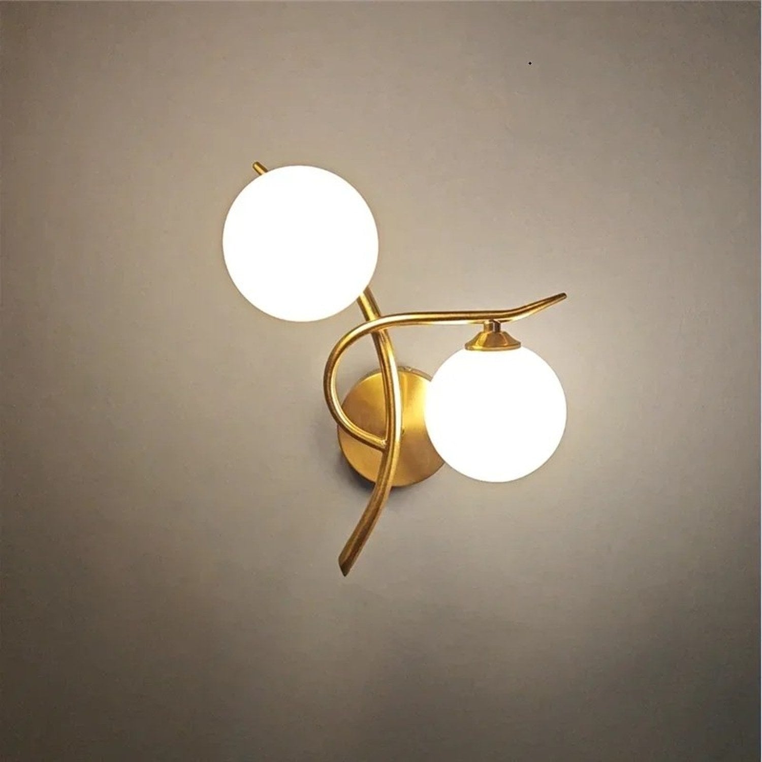 Applique murale dorée deux boules de verre dépoli sur fond neutre