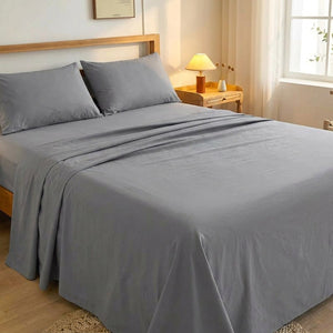 Drap plat gris en coton fait sur un lit dans une chambre lumineuse avec table de chevet en bois