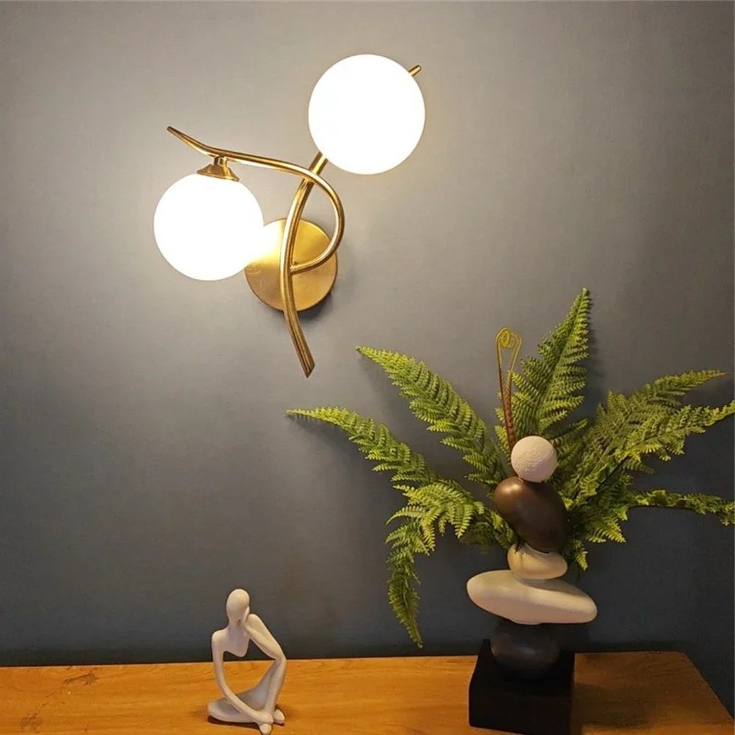 Applique murale dorée dans un intérieur avec plante et sculpture
