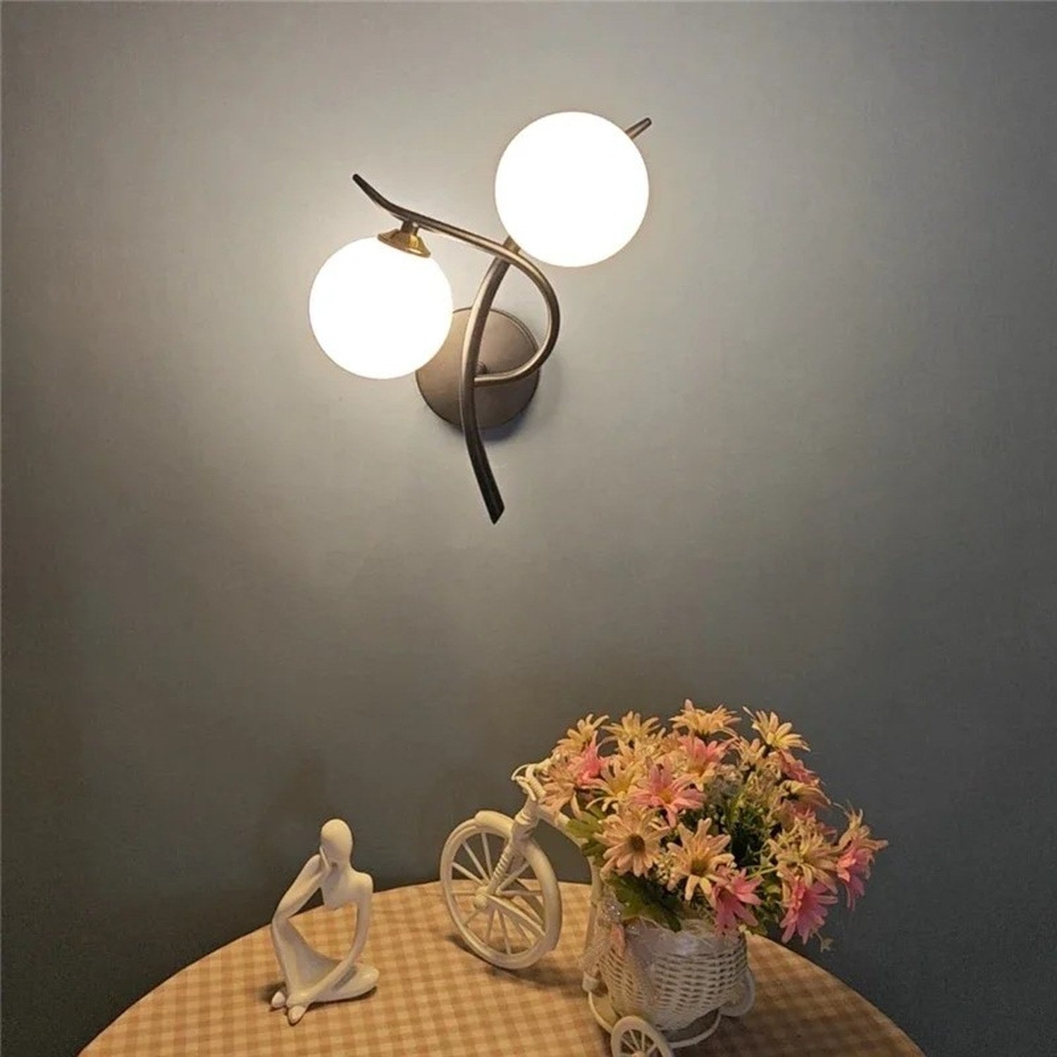 Applique murale dorée sur un mur bleu-gris avec table ronde fleurie