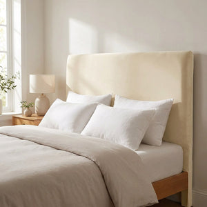 Housse de tête de lit en velours beige posée sur un lit dans une chambre lumineuse
