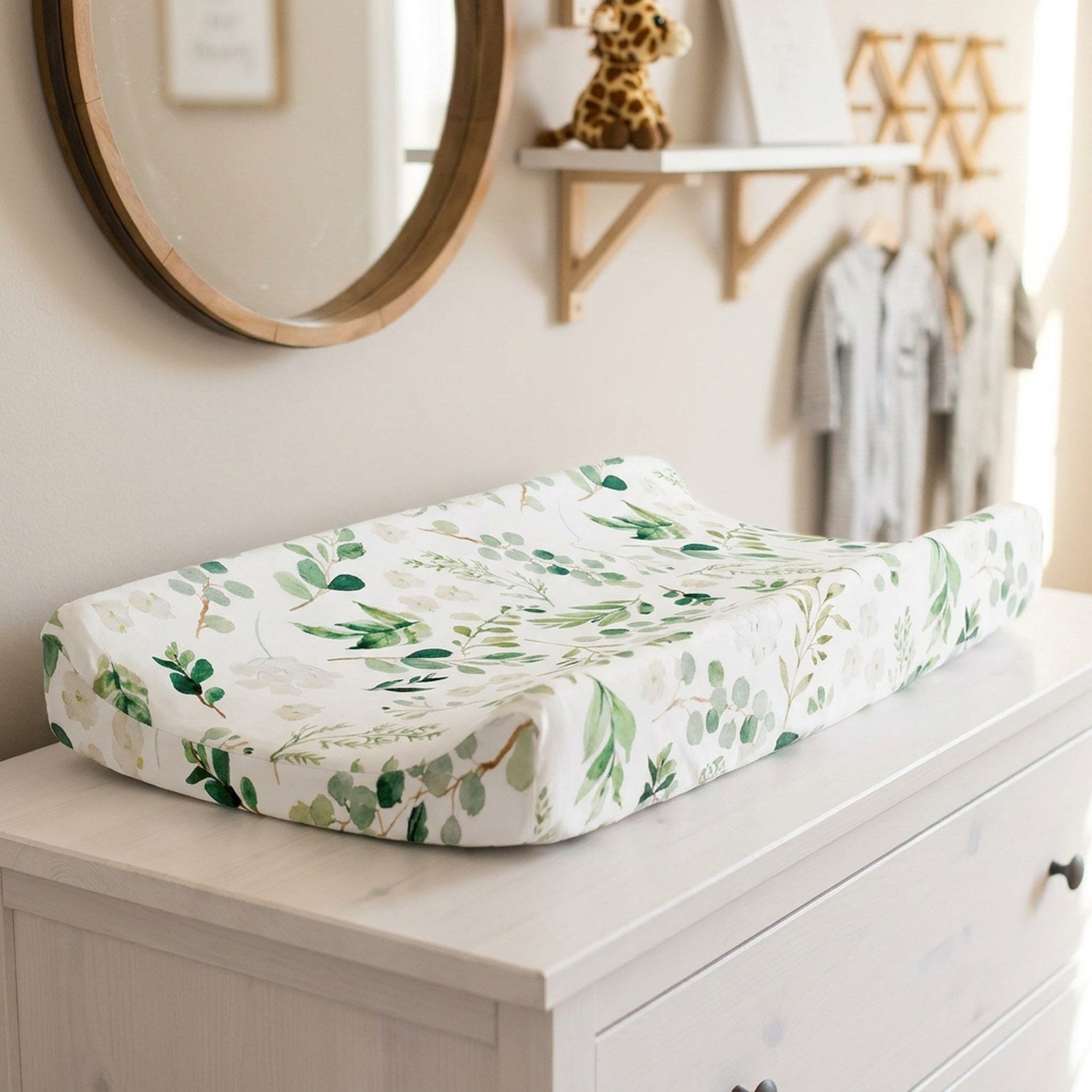 Housse de matelas à langer motif feuillage vert posée sur une commode dans une chambre de bébé