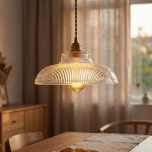 Suspension en verre nervuré transparente allumée dans un salon cosy vintage avec bokeh chaud
