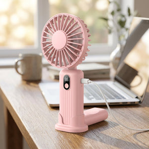 Ventilateur portable rose posé sur un bureau en bois à côté d'un ordinateur portable