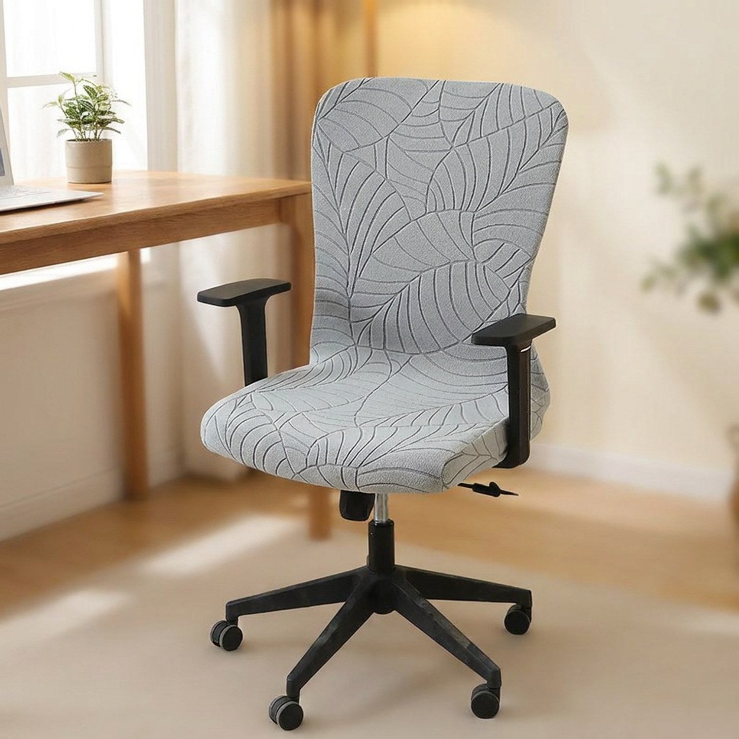 Housse de chaise de bureau grise a motif feuilles installee sur un siege pivotant dans un bureau lumineux