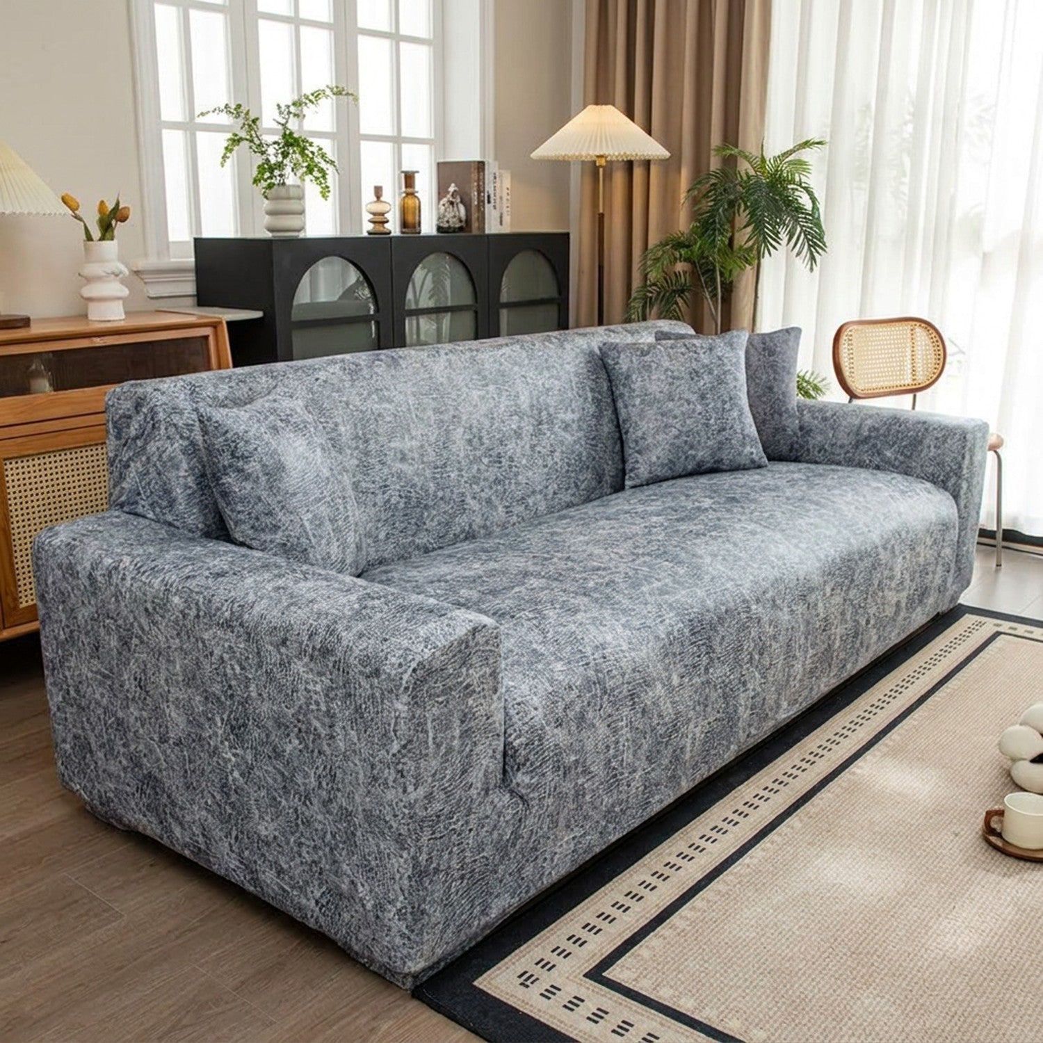 Housse de canapé jacquard gris installée dans un salon lumineux