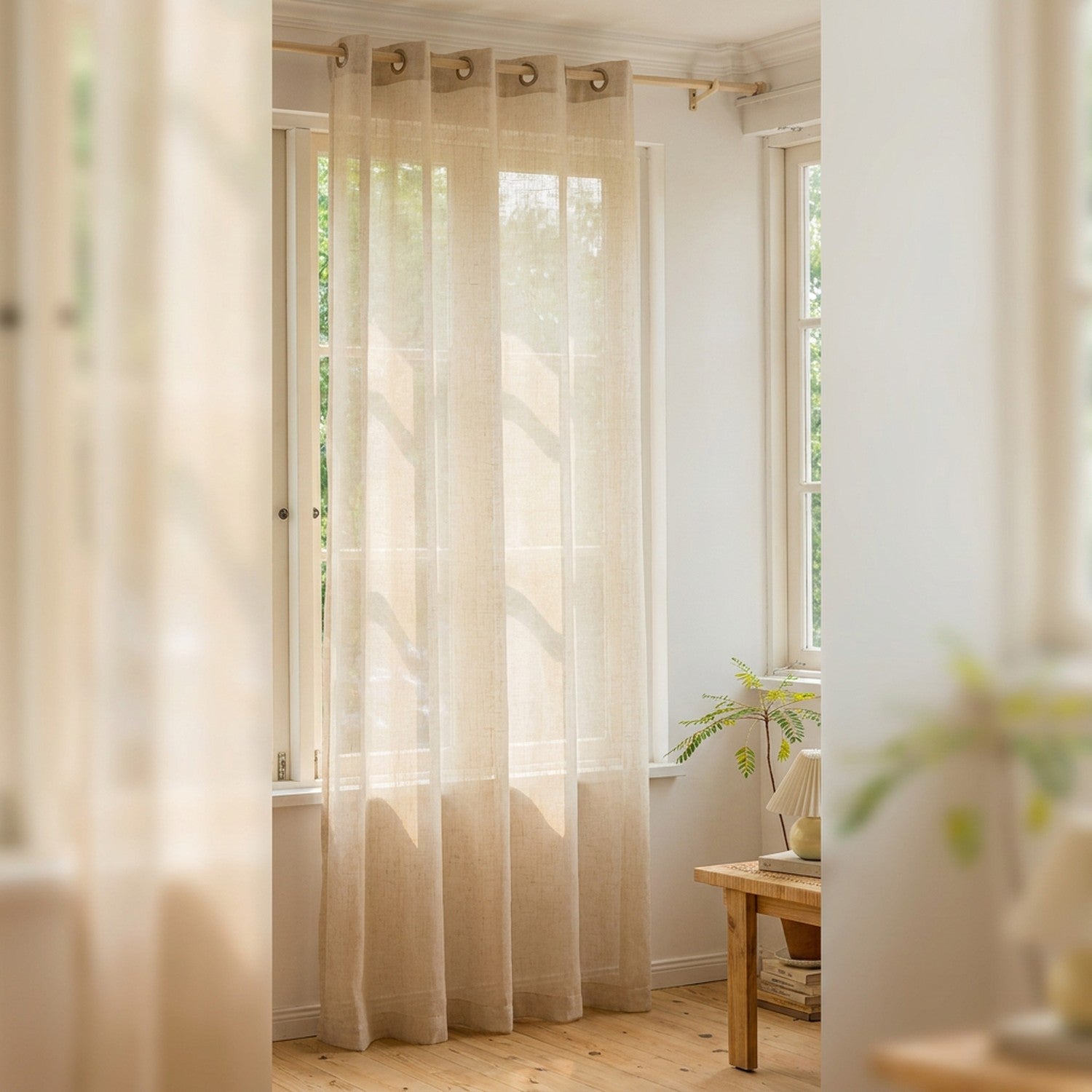 Voilage beige en voile aspect lin suspendu à une tringle devant une fenêtre lumineuse dans un salon