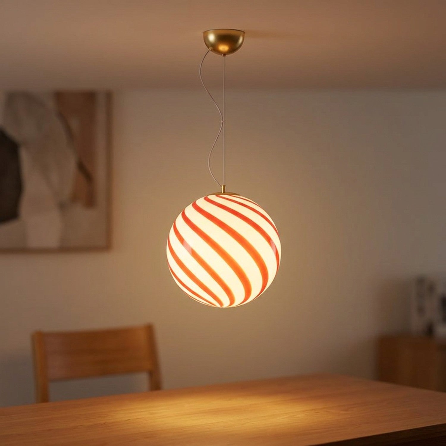 Suspension boule en verre à rayures rouges en spirale suspendue dans un salon lumineux et chaleureux
