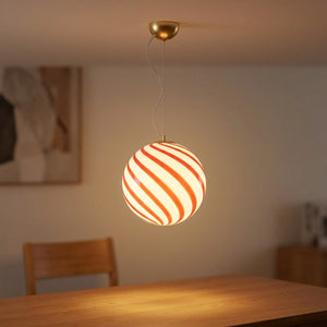 Suspension boule en verre à rayures rouges en spirale suspendue dans un salon lumineux et chaleureux