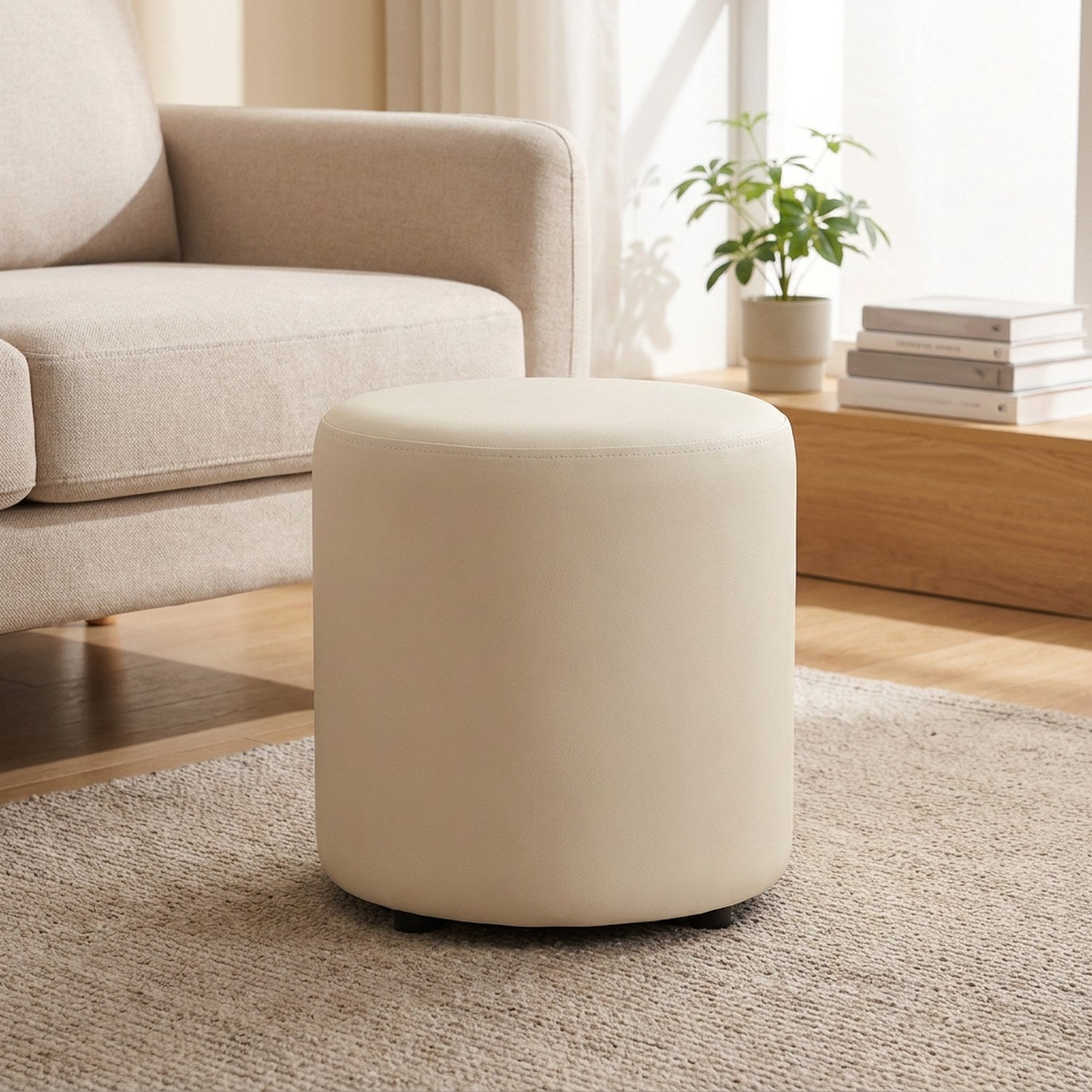 Tabouret pouf rond crème en bois massif posé sur un tapis dans un salon chaleureux