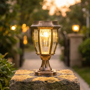Lanterne solaire rétro bronze allumée sur un pilier en pierre dans un jardin au crépuscule