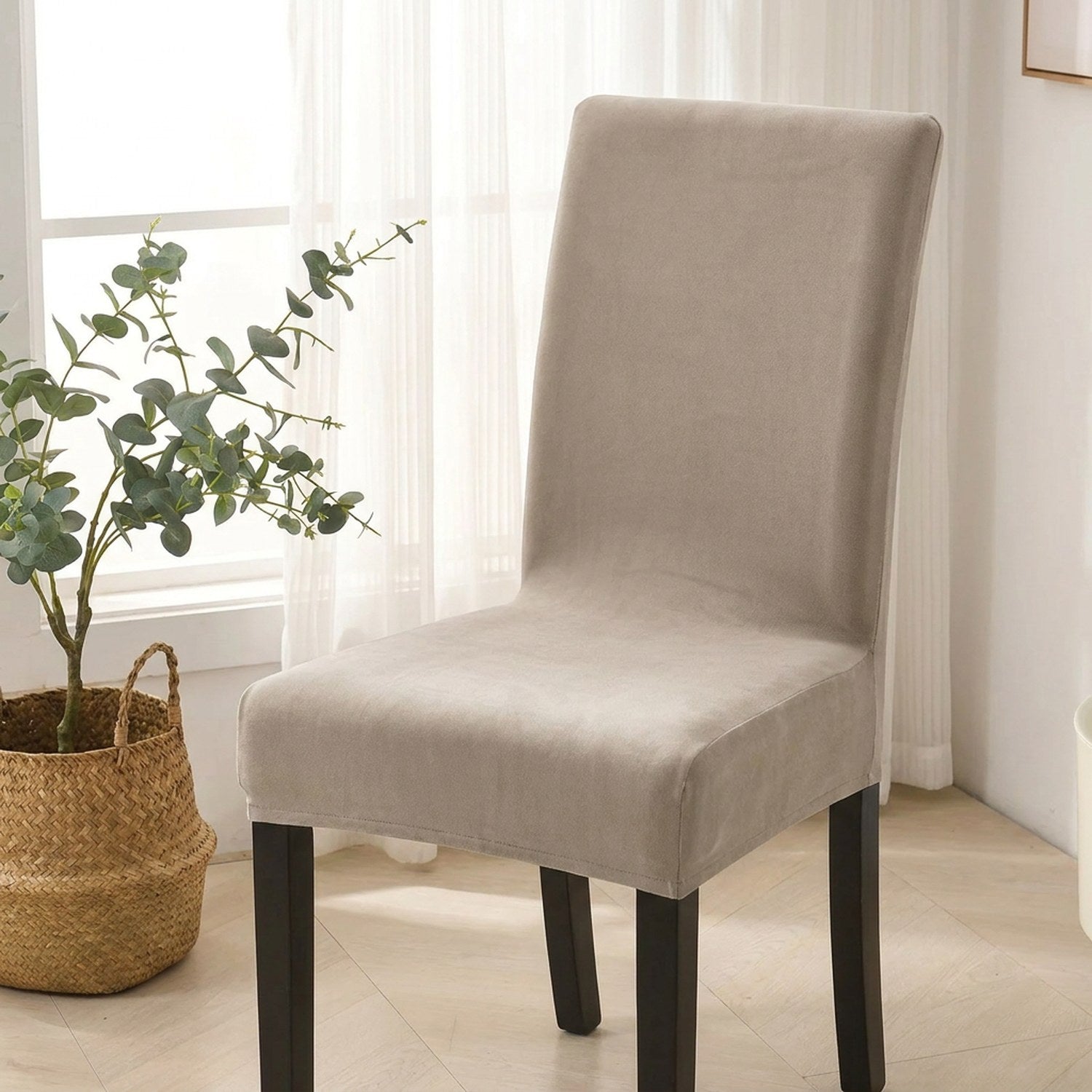 Housse de chaise de salle à manger beige extensible près d'une fenêtre lumineuse