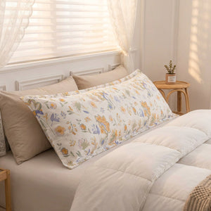 Taie d'oreiller longue à motifs floraux pastel posée sur un lit cocooning
