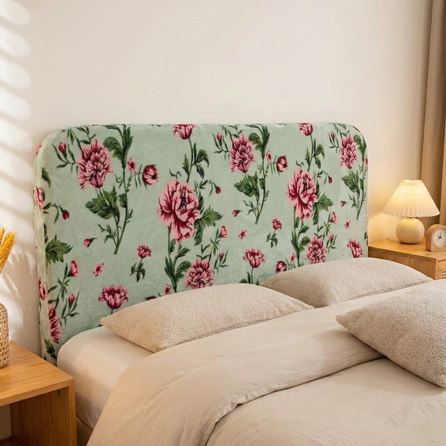 Housse de tête de lit en velours vert imprimé de roses installée sur une tête de lit dans une chambre chaleureuse et lumineuse