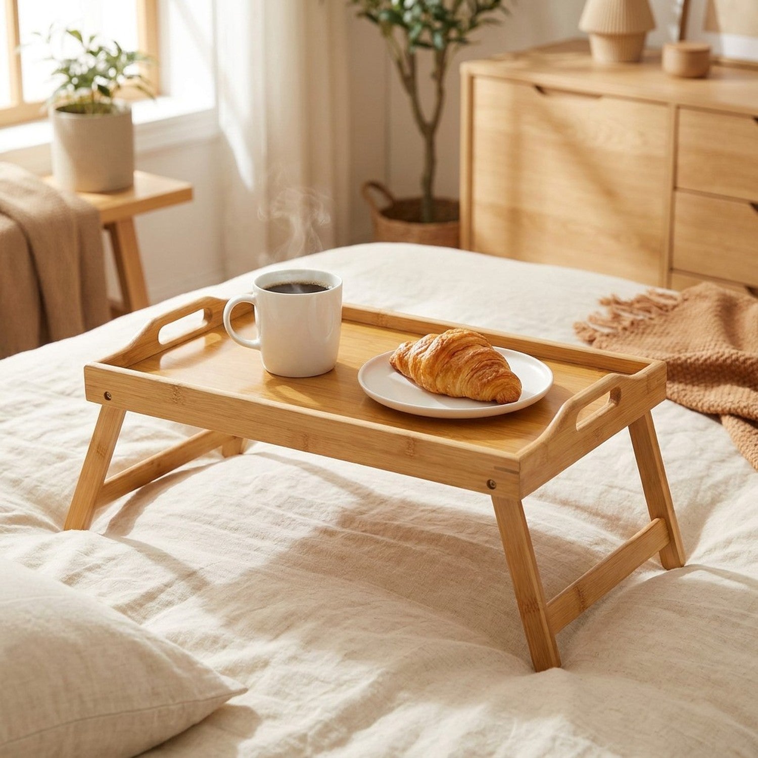 Plateau de lit en bambou pliable avec tasse de café et croissant sur un lit cosy