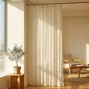 Rideau voilage en gaze translucide blanc suspendu devant une fenêtre lumineuse dans un salon chaleureux