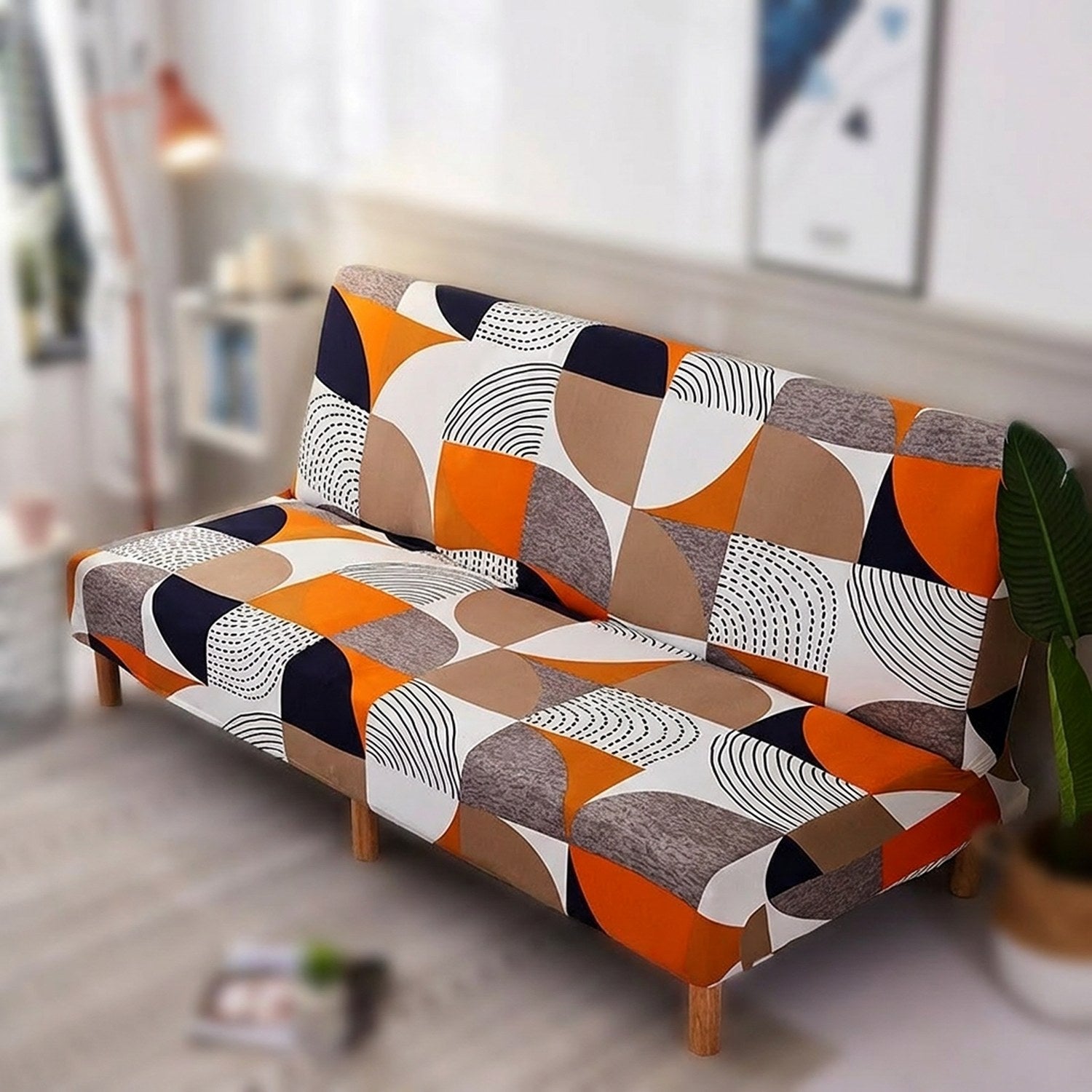 Housse de canapé-lit extensible imprimé géométrique orange sur canapé clic-clac dans un salon lumineux