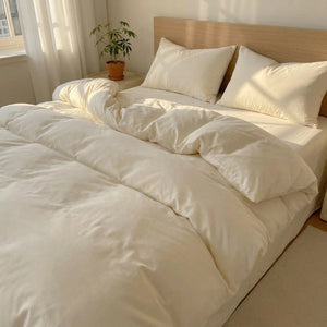 Parure de lit 4 pièces en coton lavé ivoire installée sur un lit dans une chambre lumineuse et cosy