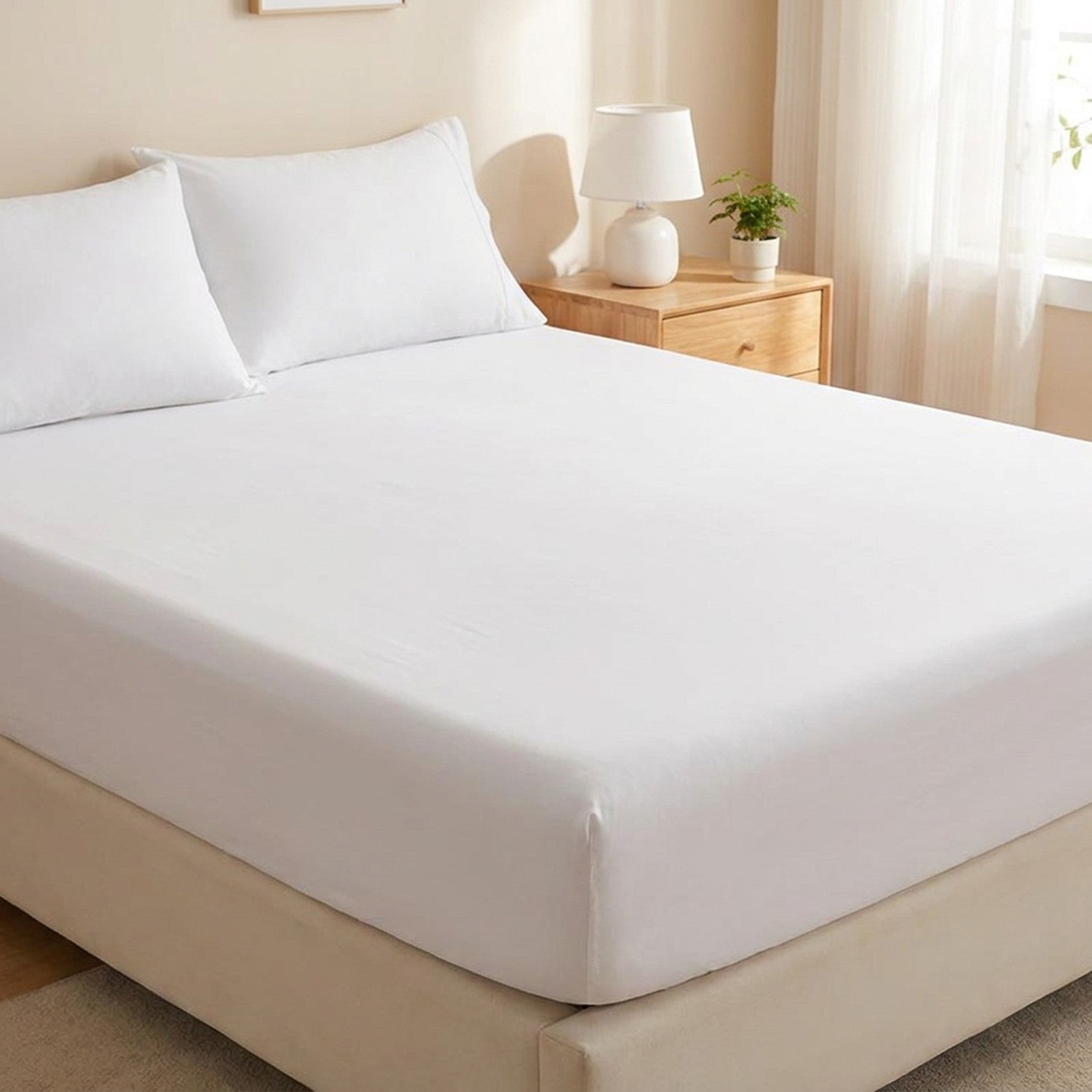 Drap-housse délavé blanc tendu sur un matelas avec oreillers assortis dans une chambre lumineuse