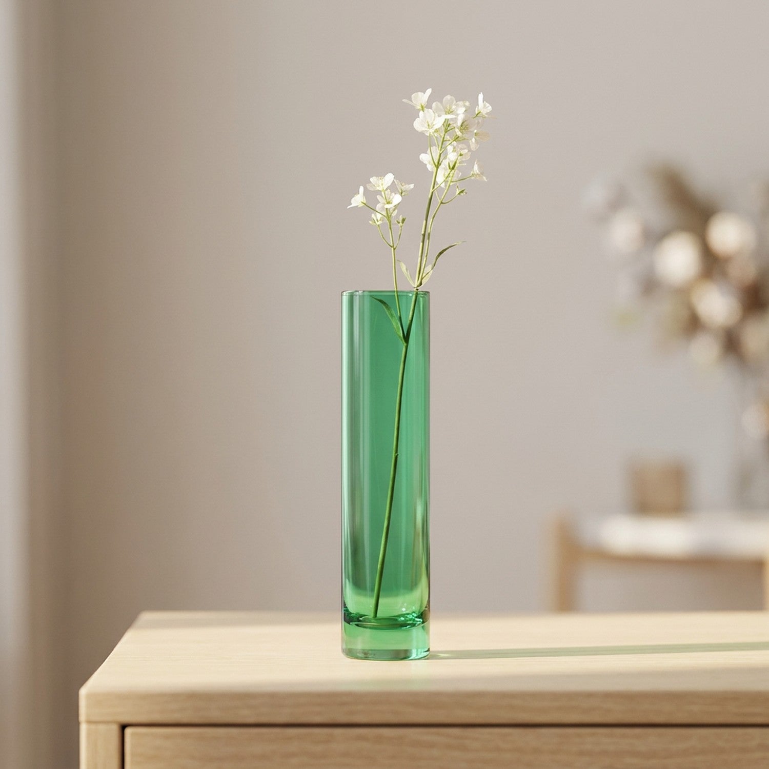 Vase en verre coloré vert au tube fin avec une fleur blanche sur une console en bois