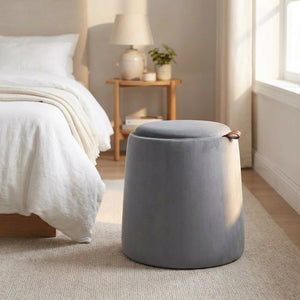 Pouf coffre de rangement rond en velours gris dans une chambre lumineuse