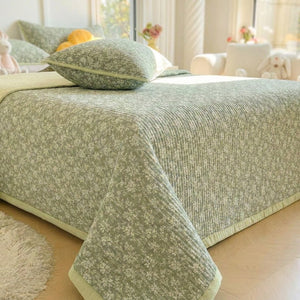 Couvre-lit matelassé vert à motifs floraux posé sur un lit fait dans une chambre lumineuse