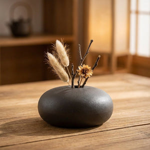 Vase céramique ikebana matte gris forme goutte eau avec branches séchées sur table en bois