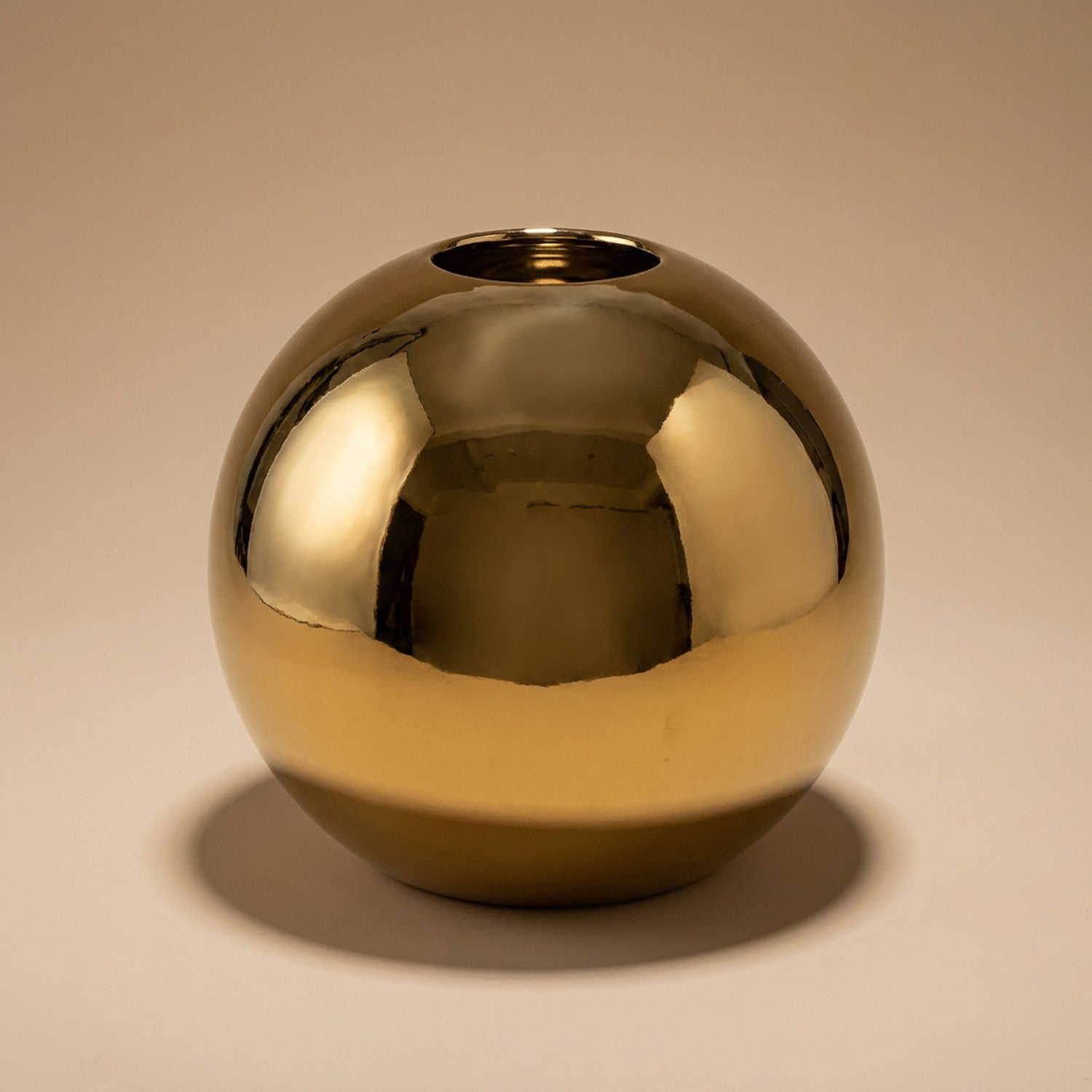 Vase boule en céramique dorée sur fond neutre beige, forme sphérique parfaite