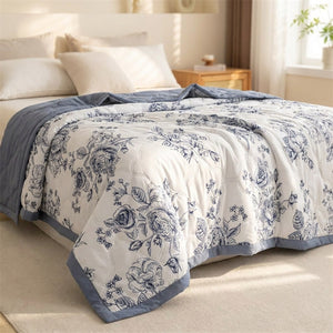 Couette d'été à motif floral bleuté posée sur un lit fait dans une chambre lumineuse
