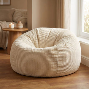 Pouf blanc en velours côtelé posé au sol dans un salon chaleureux