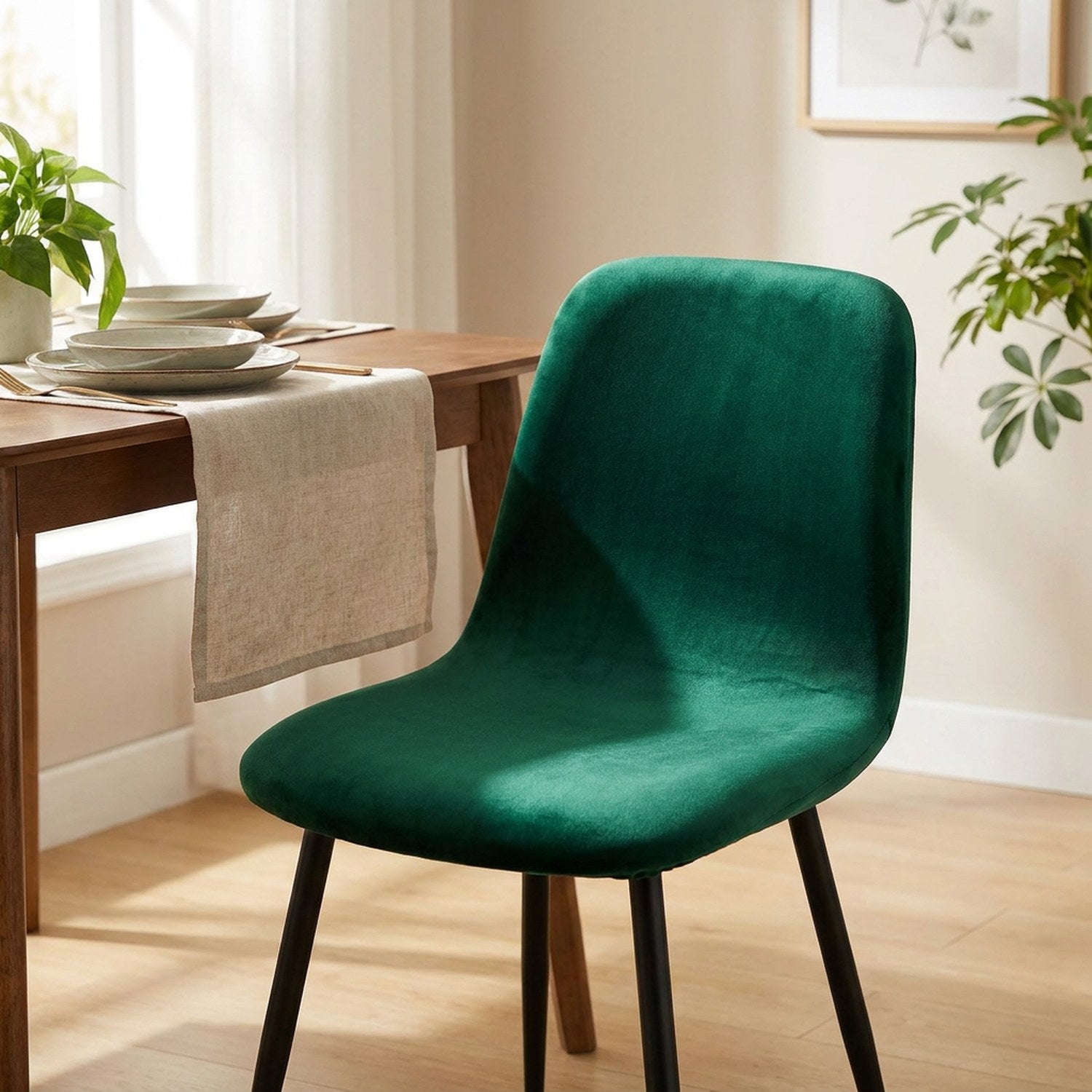 Housse de chaise en velours vert émeraude sur une chaise à dossier court dans une salle à manger
