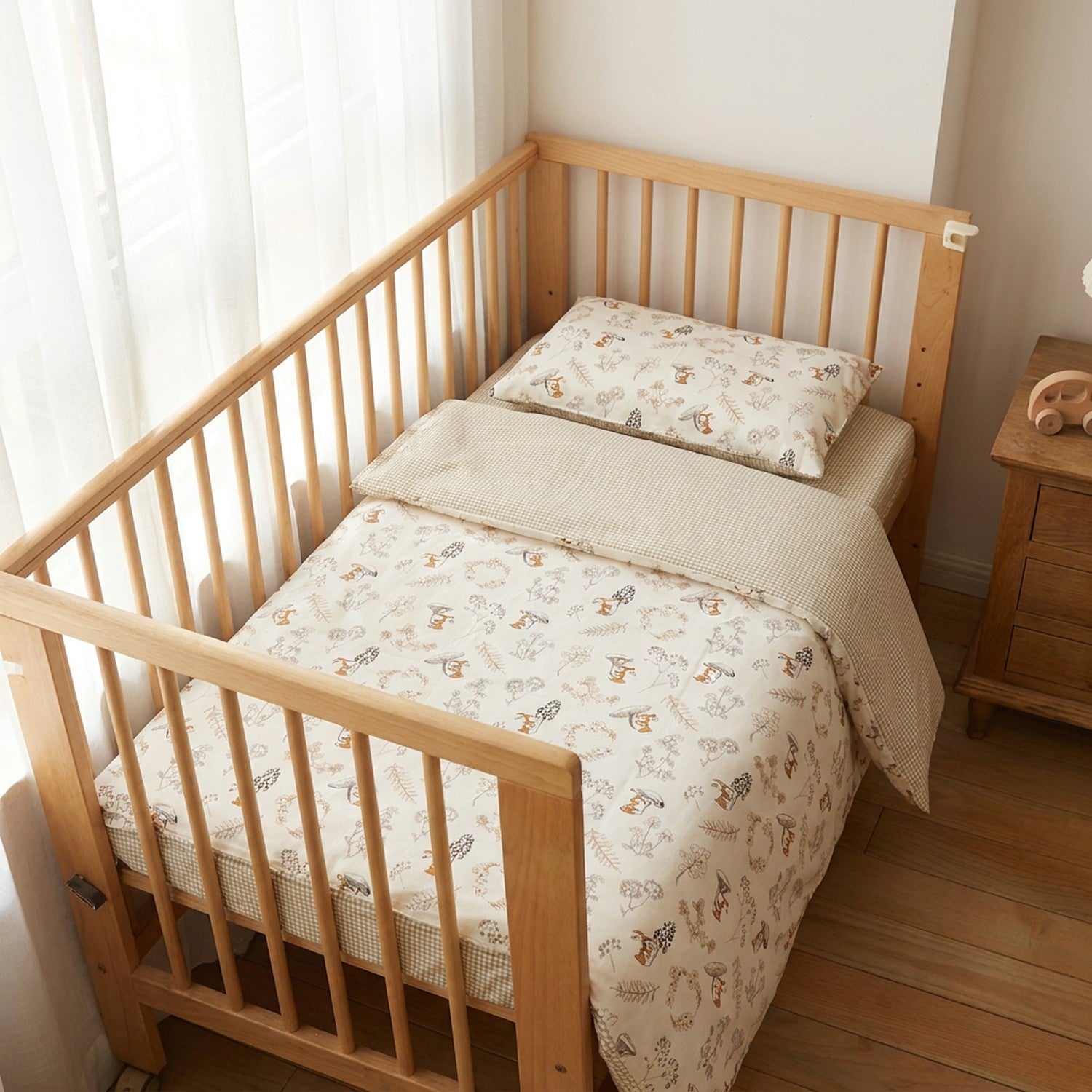 Parure de lit bébé en coton aux motifs animaux installée sur un berceau en bois clair