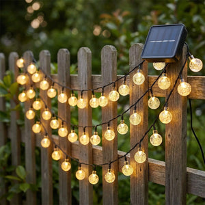 Guirlande lumineuse solaire LED à globes de cristal sur clôture bois jardin crépuscule